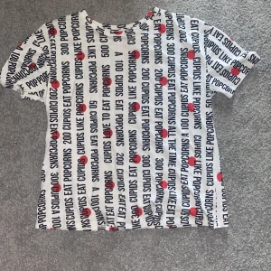 Oversized t-shirt - Vit Tshirt med svart text och röda detaljer. Vet inte exakt storlek, men är oversized på mig som har strl S/M i vanligafall. 