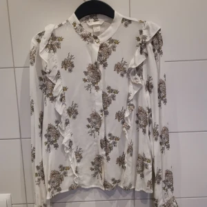 Vit blommig skjorta  - Vit, blommig skjorta med fina detaljer. Helt ny, från H&M i storlek 38✨ Frakt tillkommer 💕