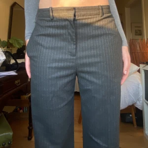 Kritstrecksrandiga kostymbyxor - Kritstrecksrandiga mörkgråa kostymbyxor från Lindex. Jag är 176 och de når enda ner till fötterna! 