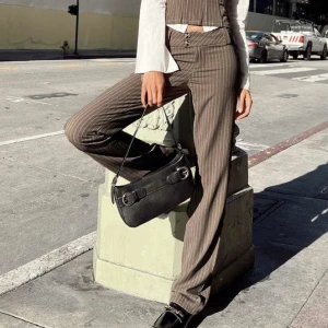 Pinstripe lågmidjade byxor MOTEL - Trendiga lågmidjade bruna byxor med ränder. Ej använda då de är för små. Storlek 80-84 cm midja. Innebenslängden cirka 82 cm