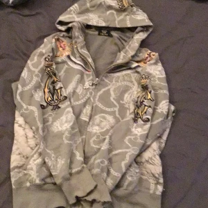 Christian audigier zip up - lite sliten och är ganska tunn perfekt för våren står S är mer som M Den är typ grå grön