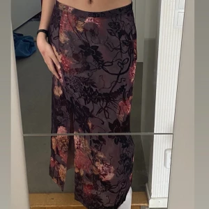 vintage blommig kjol - superfin lila vintagekjol med blommigt mönster från elinette i storlek 40. har en slit och dragkedja på baksidan. 