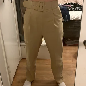 Kostymbyxor  - Säljer dessa snygga beiga kostymbyxor som jag köpt second hand för att de tyvärr var för stora. Skärpet ingår! Säljer även samma fast i grönt. (Lite smutsig spegel men plagget är helt rent)💖