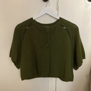 Kortärmad kofta - Sticka kortärmad kofta/ topp. Den är cropped i passformen och knäpps med två knappar.