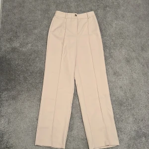 Beiga kostymbyxor  - Helt oanvända kostymbyxor i en ljus beige färg, långa, breda och lite genomskinliga