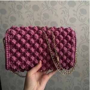 Bubbel väska - Detta är en bubblig väska i rosa/lila färg. Garnet är ett sk "polyester cord" som är stabilare och hårdare än vanligt bommuls-/akrylgarn.  längd: 25.5cm  höjd: 16cm  djup: 4.5cm Frakt tillkommer♥️