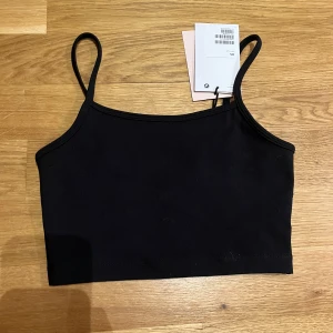 Svart magtop med smala axelband - Helt oanvänd top säljes på grund av för liten för mig. Går att använda som träningstop. 