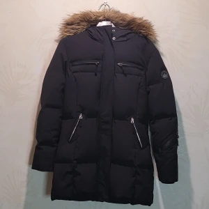 Jacka - Svart Jan Mayen dunjacka med pälsluva. Pälsen på luvan är avtagbar. Jackan går över höfterna. 90% dun 10% fjäder. Nyskick, använd endast fåtal gånger.Jackan har inga fel och är välbevarad, inga fläckar, inget sönder. Fler bilder kan skickas.Nypris 3500 kr