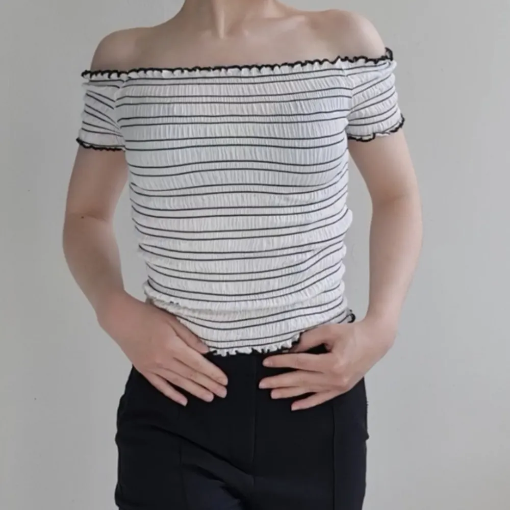 Vit- och svartrandig, ribbad off shoulder topp med krusade kanter. Mycket stretchig i mjukt tyg, i bra skick. . Toppar.