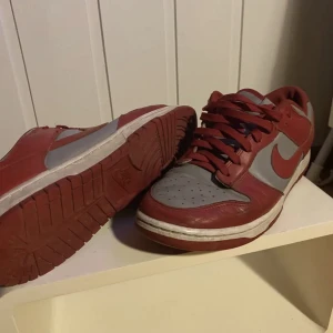 Nike Dunks - Nike Dunk Grey Varsity Red size 44,5 Skick: se bilder (hål i hälen annars som vanligt) Nypris: 1,4k