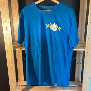 T-shirt med tryck - Superfin turkosaktig T-shirt med tryck på bröstet och ryggen  Aldrig använd