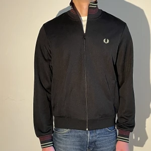 Fred Perry track jacket M - Jättesnygg track jacket från fred Perry! Sparsamt använd så den är i 9/10 skick. Storlek M och sitter väldigt bra. Nypris var 1400kr så passa på 🙌