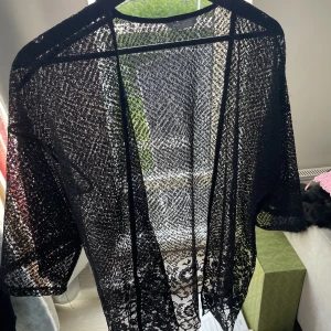 Svart Kofta i spets från Lindex - Svart spetskofta med mönster i form av rosor och annat. Barnavdelning storlek 152-170 men den är väldigt stor och passar mig som är storlek XS / S och min mamma kan även använda den som brukar har S eller M. Den är i bra skick!