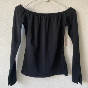 Topp - Offsoulder topp från Nelly. Helt ny, aldrig använd! Slit nere i ärmarna