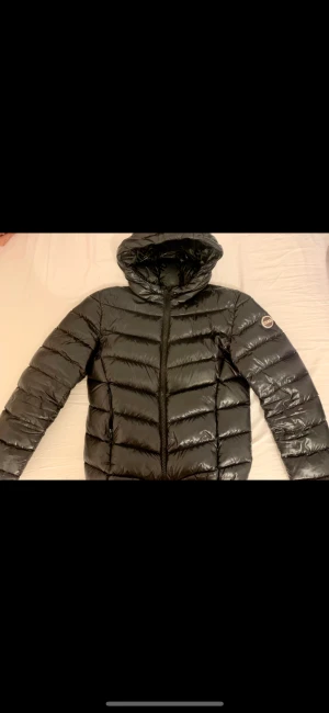Colmar jacka - Glansig Svart colmar jacka perfekt för höst och vinter, på ena fickan har dragkedjan gått sönder samt ett hål på insidan av fickan. (Inget som syns utifrån)  Stl 36 (42 Italensk stl)