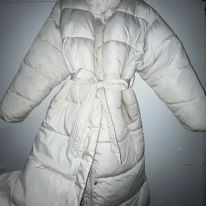 Zoe täckjacka. Vadderad vinterjacka från BikBok  - Vit varm vadderad vinterjacka med band att knyta vid midjan. Jackan är varm men också figurnära och formar fint. (Kommer att kemtvättas innan leverans). Köpt för 999kr. Pris kan diskuteras vid snabb affär ❤️👍🏽