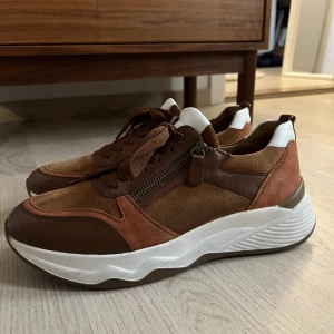 Sneakers från Gabor i mocka/skinn - Sneakers från Gabor Comfort i mocka/skinn. Snörning samt dragkedja som gör de smidiga att ta på sig.   Storlek 40 (US 9). Använda ett fåtal gånger så de är rena och i fint skick.   Finns i Solna/Råsunda, kan även mötas vid Gärdet eller Kungsträdgården.