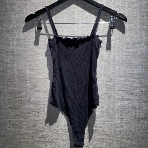Body | Brandy Melville - En jättefin svart body med väldigt vacker och unik urringning från Brandy Melville i S. Den är lite nopprig, därför säljer jag för nedsatt pris. Skriv privat för mer bilder och info