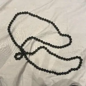 Ett lång pärlhalsband med mörkblå/svarta pärlor 