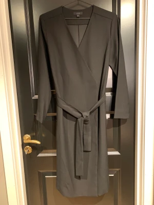 COS omlottklänning - Svart långärmad omlottklänning från COS i storlek 38, endast använd vid ett tillfälle så därför som nyskick