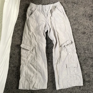 Ljusgrå cargo byxor  - Ljusgrå cargobyxor från Urban outfitters. Dom har två små färg fläckar på ena benet men inget stort. Dom är låg midjade och super sköna i lite varmare väder 