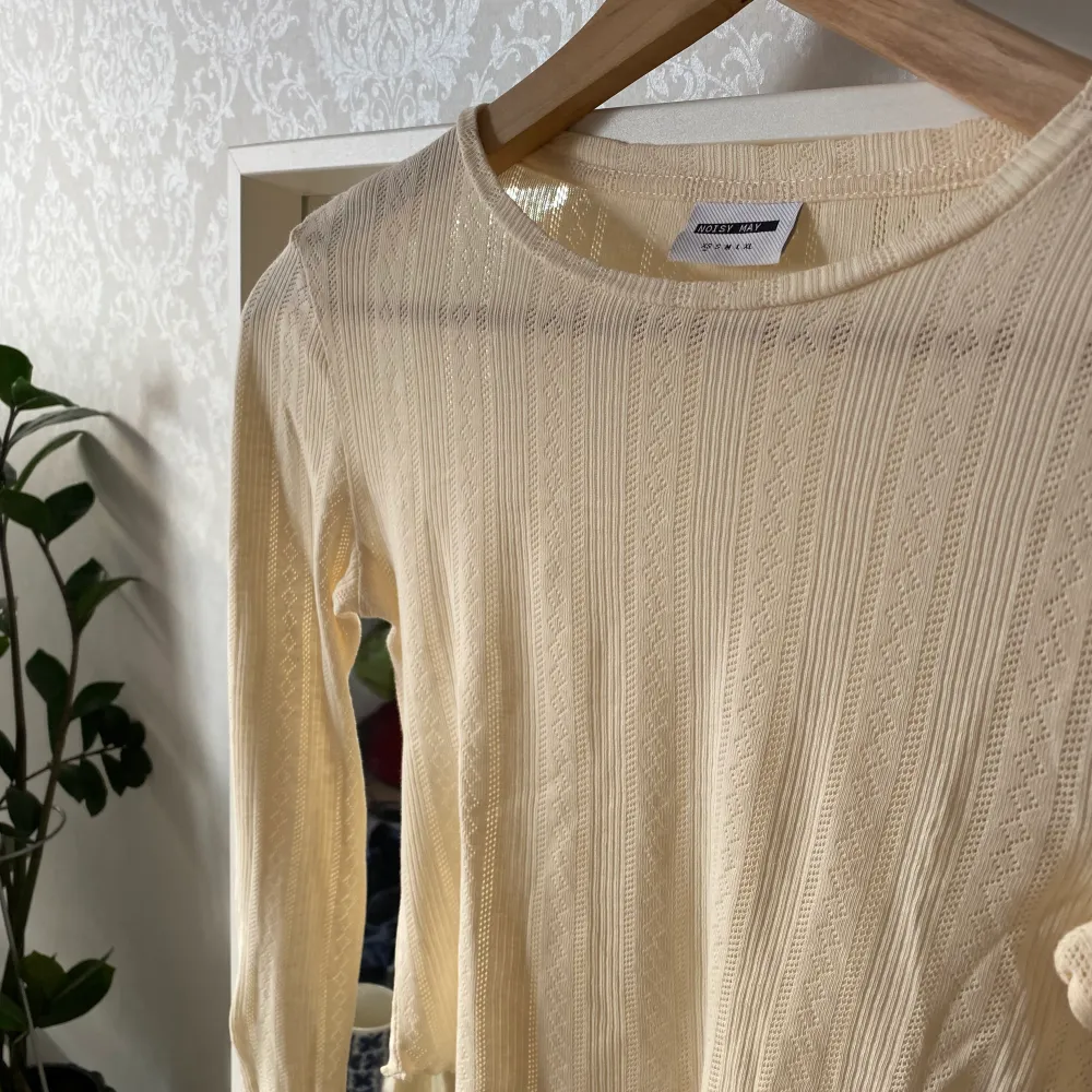 En beige långärmad tröja med mönster och volanger, använd ett fåtal gånger men är som ny. Stretchig i materialet och kroppad.. Toppar.