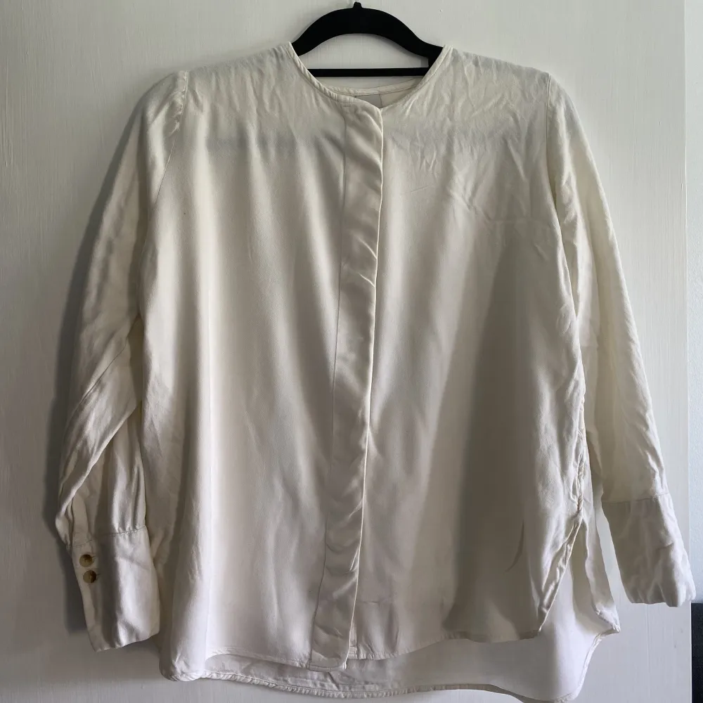 viscose off-white shirt good for a size XS/S, covered fly and nice minimal collar. . Blusar.