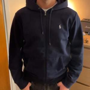 Mörkblå zip-hoodie från Ralph Lauren. I fint skick.   Storlek M  Nypris: 1800kr 