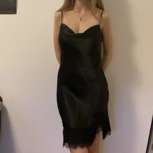 Svart klänning - Svart klänning i satinliknande material med spets längst ner 🤍 endast använd en gång