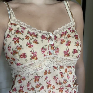 Vintage blommig topp - Blommig topp med spets köpt på second hand i fint skick, går att knyta både fram och bak, står inget märke.