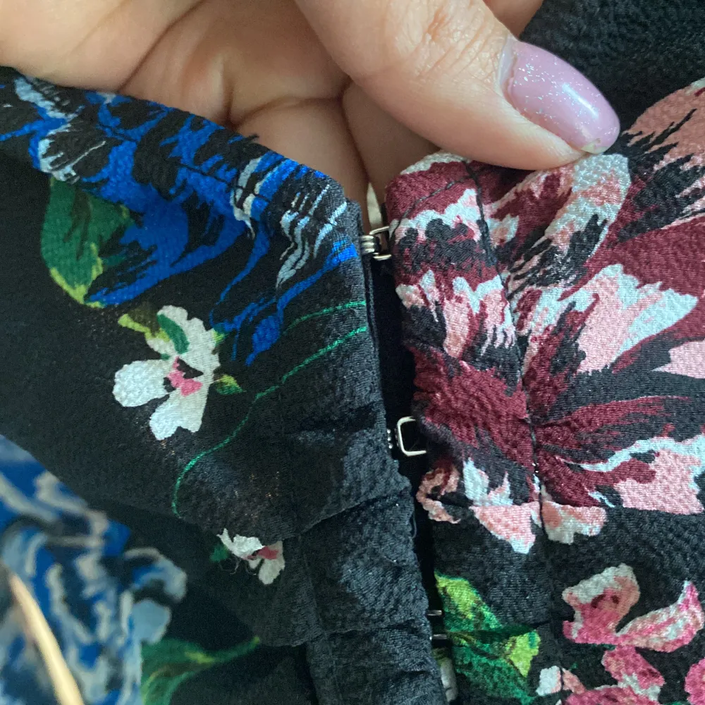 Blommig svart blus, med fina detaljer på ärmarna och man stänger den med små liknande krok som gör att formen blir fint runt midjan . Blusar.