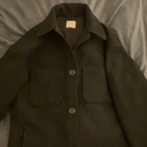Svart lång kappa - Går över rumpan, köpte den i vintras på h&m för 650kr,  säljer pga använder inte den längre🙌🏽 Fråga om mer bilder!