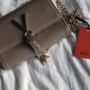 Valentino väska - Säljer en oanvänd valentino väska som är köpt på Åhléns. Beige/brun färg. 💕💕