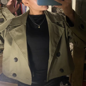 Grön trenchcoat - Aldrig använd därför säljer jag. Säljer för 500 inklusive frakt, pris går att diskuteras vid snabb affär. Perfekt till höst/våren 