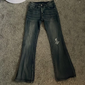 Lågmidjade jeans - Ett par lågmidjade blåa utsvängda jeans med hål ifrån shein i storlek xs. Hålet har jag gjort själv. Frakten diskuteras privat