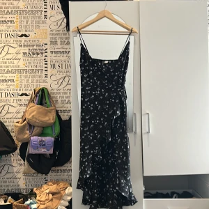 Svart knut klänning  - Svart klänning som knyts runt midjan från HM i storlek s/m. Den har blommigt mönster och tunt tyg perfekt för sommaren.