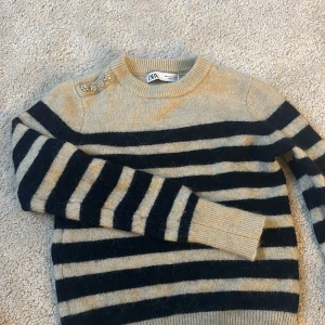 Stickad tröja från Zara - Superskön stickad tröja från Zara. Perfekta hösttröjan men säljes då den är för kort i ärmarna på mig. Stenarna på axeln föreställer 4 blommor och är en väldigt fin detalj💞