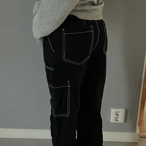 Svarta byxor - Coola svarta byxor i tyg med vita sömmar! Sitter overzised och har hög midja. Köpta på H&M och i väldigt bra skick, tyvärr använder jag dom inte längre och därför säljer jag 💞 Vid frågor besvarar jag dom jätte gärna privat💘 