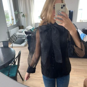 Svart blus från zara - Svart blus från zara woman, genomskinlig rygg och arm. Rosett i halsen, saknas en knapp längst ner.