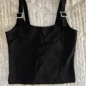 Linne med strasspännen - Svart linne med strasspännen i storlek 38 från & Other Stories. Oanvänt med lappen kvar.