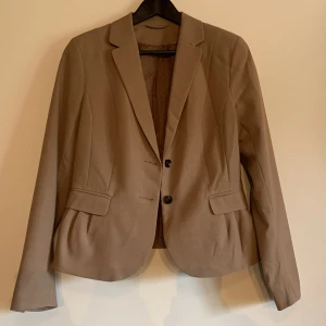 Brun kavaj  - Brun kavaj, figursydd. (omärkt). Fickor finns men är osprättade. Använd ett fåtal gånger. Ingen storlek märkt, men skulle säga XS-S.  