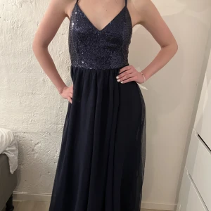 Klänning - (2/2) Mörkblå långklänning med glitter. Köpt på bubbleroom för 1000kr och säljer för 800. Pris kan diskuteras. (En lånad bild) finns i storlekarna 38 och 40.  Felköp då de ej passade festen och hann ej returnera. 