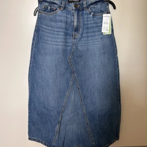 Långkjol i jeans - Oanvänd långkjol i jeans! Strl 34. Liten spricka under gylf som fanns vid köp men inget som syns när kjolen är på. 
