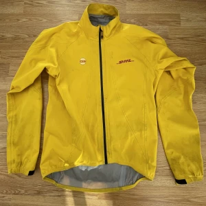 DHL Jacka - Äkta DHL jacka. Storlek Large, men lutar mer mot M imo. Lite skitig på ärmarna som kan ses på bilderna, aldrig provat tvätta så kanske försvinner i en tvätt.