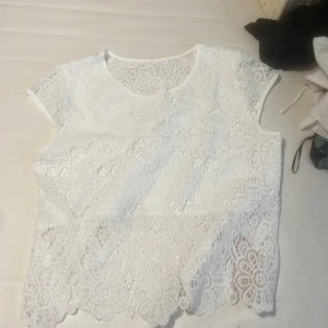 ”Blommig” tshirt - Ihålig vit tröja i storlek L. Det är tyg för bysten så det inte syns igenom. Den är fin men har nästan en likadan så använder bara en. Köpte för typ 15-60 spänn