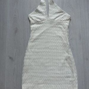 Vit halter klänning - Kort, somrig, halter neck klänning i vit med fint mönster. Storleken är xs men skulle även kunna passa xxs. Frakten betalar du själv.