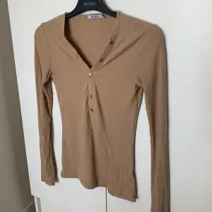 Beige långärmad topp från na-kd. Går att knäppa upp mer och även knäppa ner. Fint skick!