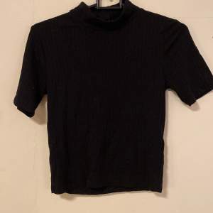 Stretchig, svart, ribbad T-shirt från ginatricot