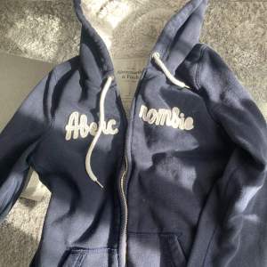 Marinblå zip hoodie från abercrombie and fitch med en supermjukt vit innandöme💘       Storlek S - men skulle säga att den passar som en xs/s.🧵   Nypriss är runt 600kr men den säljs inte längre.  Pris kan diskuteras:)💞