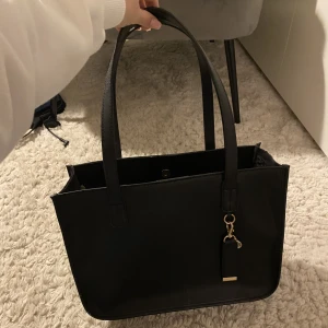 Svart väska  - Säljer denna snygga svarta väska då den inte har kommit till användning, den är som nyskick och funkar som både skolväska eller shoppingväska🩷skriv om ni har några frågor🩷#svart #väska #nyskick #shopping #skolväska #mellanstor #rymlig #supersnygg